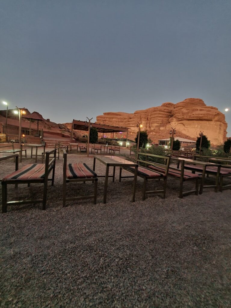 Tables and a canopy near the buffet with the lights of the surrounding camps behind.