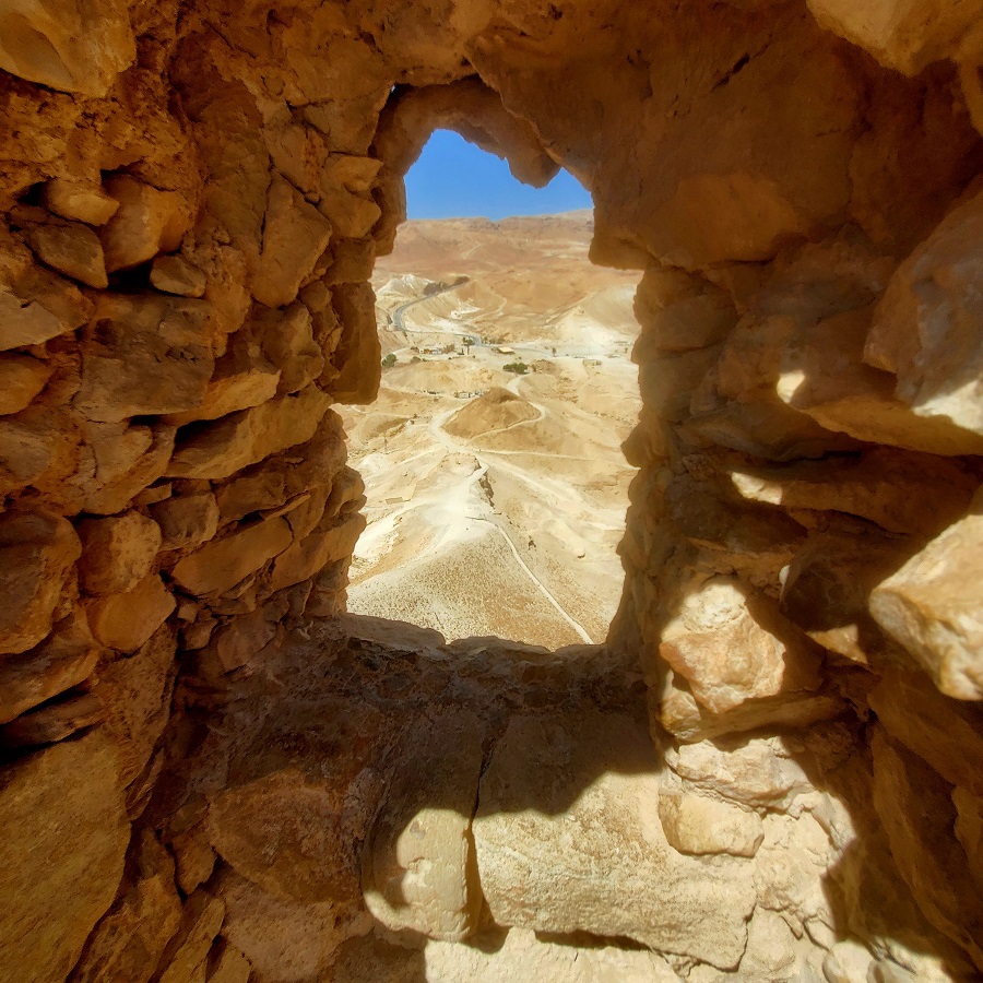 A stone window looks out from the fortress of Masada onto the Roman ramp below.