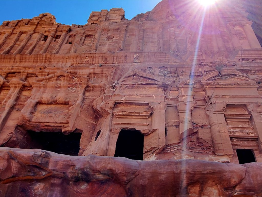 The sun peaks over the top of the stone carved Royal's Tomb in Petra.