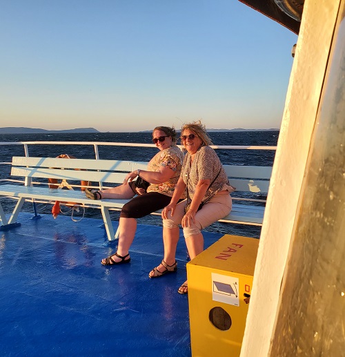 Two ladies, one with a leg up on the bench. Laugh about the spray they are getting drenched with.