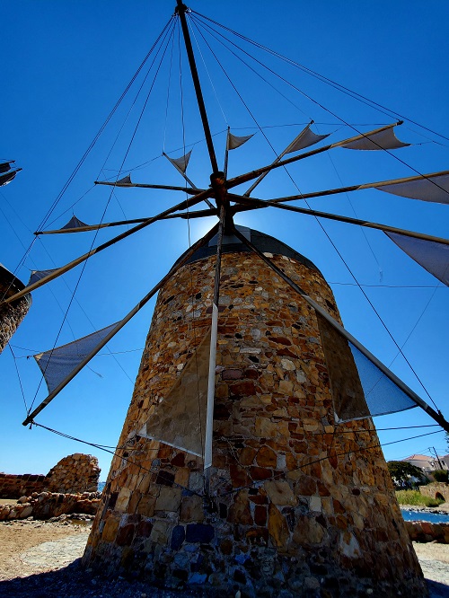 A stone windmill stands near the port of Chios. Its rigging and sails filled with wind.