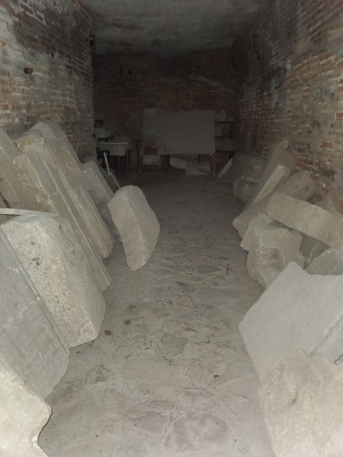 Carved stone pillars and headstones lean against the walls beyond the barriers of the princely court.