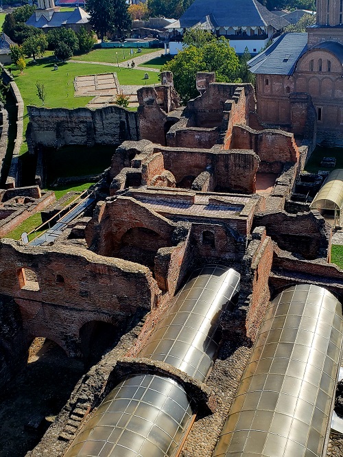 Brick walls still stand, naked of any trace of plaster. Portions are covered by a protective roof.