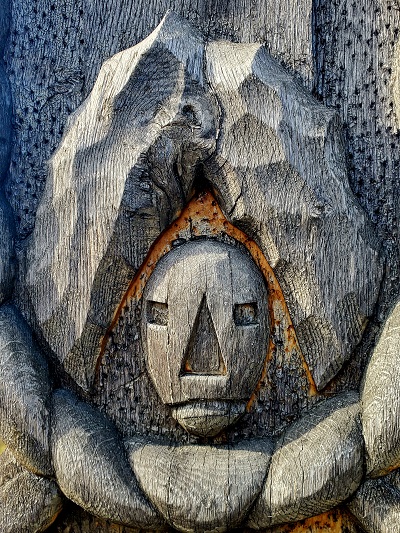 A face carved into a road side cross, grey with age between Brasov and Targovishte.