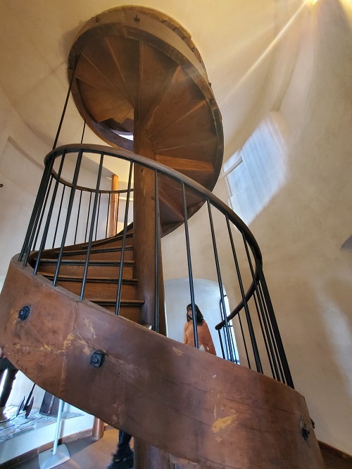 A walnut spiral staircase rises from floor to floor inside the rebuilt light color plaster wall of Chindiei Tower.